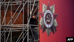 Russian worker installs a banner for the upcoming Victory Day celebrations on Moscow's Red Square, April 27