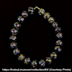 Венеційське намисто. Нанизане з чорних скляних намистин, оздоблених золотистими скісними смужками і дрібненькими голубими та червоними квітками. З колекції Національного музею народного мистецтва Гуцульщини та Покуття імені Й.Кобринського