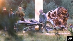 People carry a body bag away from the wreckage of a crashed private jet near the village of Kuzhenkino, Tver region, Russia, on August 24.