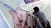FILE: A Pakistani journalist signs a banner during a protest to mark World Press Freedom day.