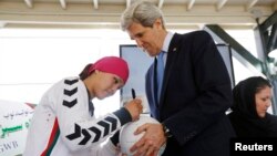 Zahra Mahmoodi (left), captain of the Afghan women's national soccer team, signs an Afghan-made soccer ball for U.S. Secretary of State John Kerry at the U.S. Embassy in Kabul last year.