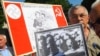 Учасник мітингу-реквієму тримає фото черепів та тлі плаката із зображенням Сталіна та Гітлера в день пам’яті жертв комуністичного і нацистського режимів. Львів, 22 червня 2011 року