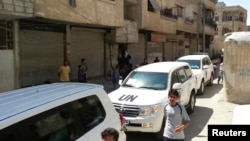 Residents gather around a convoy of UN vehicles carrying a team of UN chemical-weapons experts at one of the sites of an alleged poison-gas attack in the southwestern Damascus suburb of Mouadamiya on August 26.