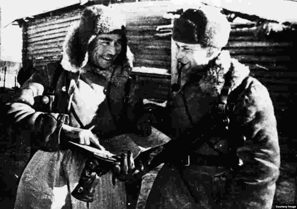 Фотография сипаттамасында "8-гвардиялық панфиловшылар дивизиясы командирлері Бауыржан Момышұлы мен Дмитрий Снегин жоспарды талқылап тұр. Мәскеу түбі, 1941 жыл" деп жазылған. 