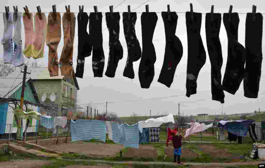 A woman hangs wash near her home in the Ukrainian village of Berdyanske, some 4 kilometers west of Shyrokyne, near Mariupol, where the use of heavy weapons has been reported. The French, German, Russian, and Ukranian foreign ministers expressed &quot;grave concern&quot; on April 14 about violations of a shaky cease-fire in separatist-held east Ukraine but pledged to continue dialogue. (AFP/Genya Savilov)