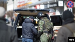 Озброєні бойовики обшукують автомобіль перед будівлею парламенту Криму в Сімферополі, 17 березня 2014 року