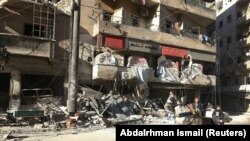 People ride a cart pulled by a horse near the damaged Hakim hospital, in the rebel-held besieged area of Aleppo.