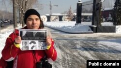 Блогер Нурали Айтеленов, не приглашенный на встречу с акимом Алматы, держит плакат рядом с рестораном, где обедают градоначальник и сетевые авторы. Алматы, 5 февраля 2014 года.