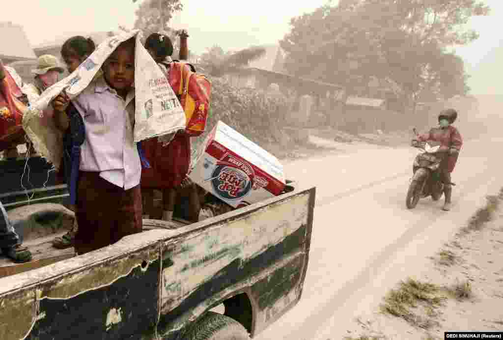 Indonesian students take cover from volcanic ash falling from Mt. Sinabung as they ride on a pickup truck and a motorcycle after the volcano erupted at Beganding village in Karo, North Sumatra, Indonesia Province. Mt. Sinabung is one of the most active volcanos in Indonesia. The 2,460-meter volcano had been dormant for 400 years before it erupted in August 2010. (epa/Dedi Sinuhaji)