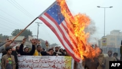Pakistani demonstrators shout slogans beside a burning U.S. flag during a protest against drone strikes in Multan on January 3.