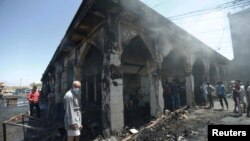 People gather at the site of a suicide attack at the entrance of the Shi'ite Mausoleum of Sayid Muhammad bin Ali al-Hadi in Balad, north of Baghdad, on July 8.