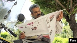 Iran, Tehran -- A man reads a newspaper