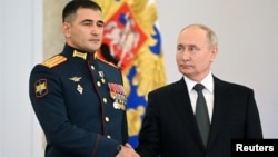 Russian President Vladimir Putin shakes hands with Lieutenant Colonel Sultan Khashegulkov during a ceremony to present Gold Star medals to service members in Moscow on December 8.