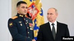 Vlagyimir Putyin a frissen kitüntetett katonák egyikével Moszkvában 2023. december 8-án