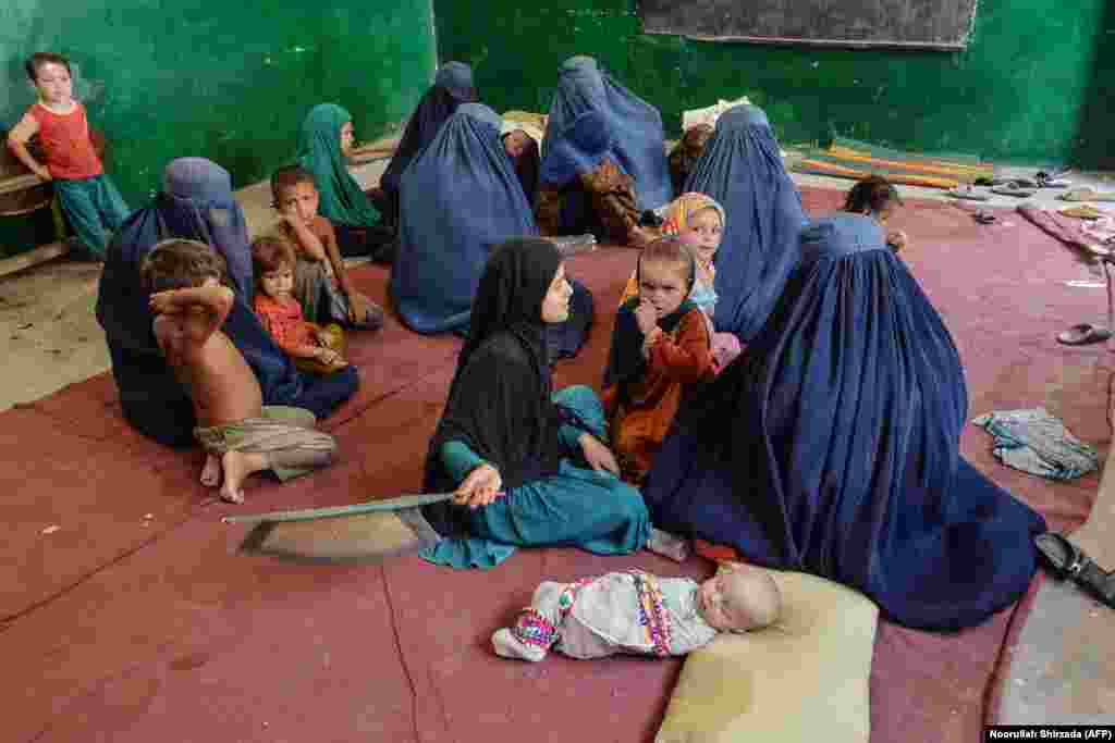 Жанчыны і дзеці адпачываюць у школе ва ўсходняй афганскай правінцыі Кунар 7 жніўня пасьля таго, як пакінулі свае дамы, каб схавацца ад баёў.