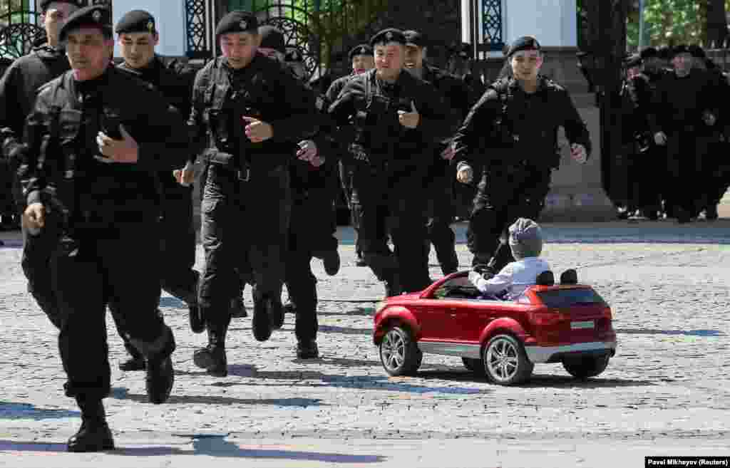 A child looks on as Kazakh police officers run to detain antigovernment protesters during a rally in Almaty on May 1. (Reuters/Pavel Mikheyev)