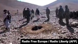 A RFE/RL video grab shows Afghan men stoning Afghan woman Rokhsana (C, in hole) to death in Ghalmeen, Afghanistan's Ghor province. Local officials say the incident happened in October. 