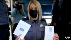 A Horvátország és Szlovénia közötti breganai határátkelőhelyen egy rendőrnő az EU digitális Covid útlevelét mutatja 2021. június 2-án