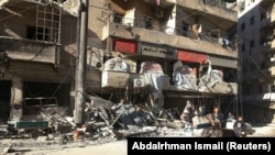 People ride a cart pulled by a horse near the damaged Hakim hospital, in the rebel-held besieged area of Aleppo.