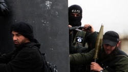 A member of the Al-Nusra Front, with an Al-Qaeda flag on his jacket (center), holds a position with fellow members of the militant group on the outskirts of Aleppo, Syria. (file photo)