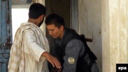 A policeman frisks a man as he enters a polling station in a high school in Kandahar Province on August 19.