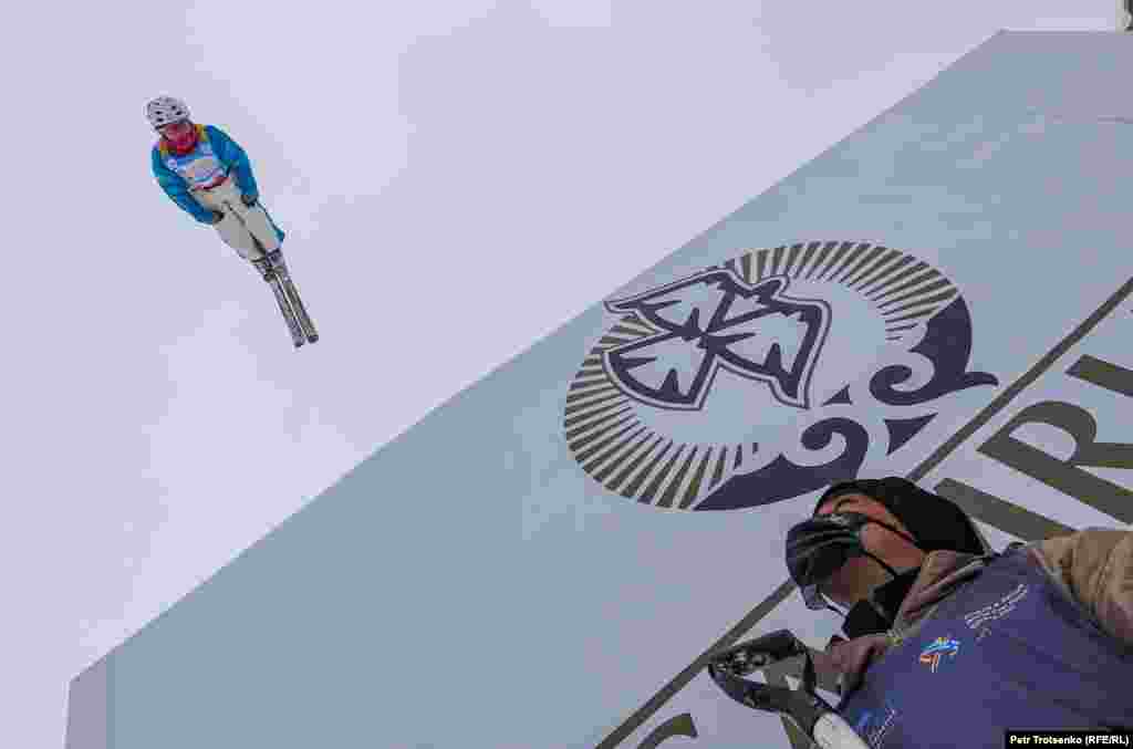 Спортшы шаңғымен трамплиннен төмен қарай сағатына 50 километрден асатын жылдамдықпен зымырап, әуеде күрделі акробатикалық элементтер орындайды.