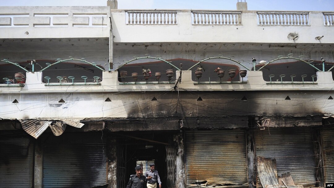 Pakistani police investigate the site of a burned market in a violence-hit western neighborhood of Karachi of July 8.