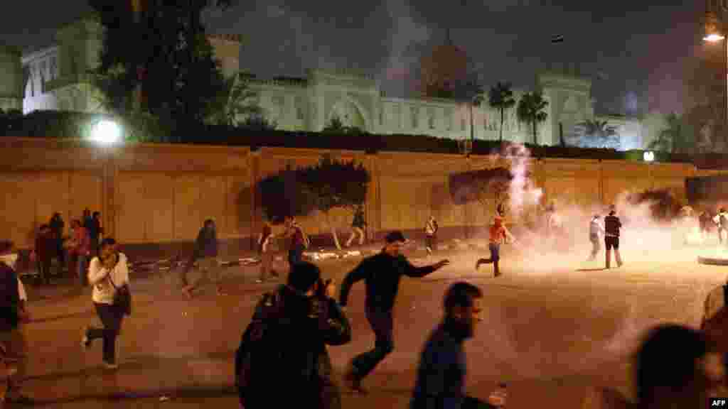 Antigovernment protesters run away from tear gas as they try to remove barriers outside the presidential palace in Cairo during a demonstration against President Muhammad Morsi&#39;s decree widening his powers. Tens of thousands of demonstrators encircled the presidential palace after riot police failed to keep them at bay. (AFP/Mahmoud Khaled)