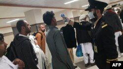 Before the flight suspension, an airport official checks the temperature of a passenger upon his arrival at the Bacha Khan International Airport in Peshawar.