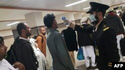 An airport official checks the temperature of a passenger upon his arrival at the Bacha Khan International Airport in Peshawar on January 27.