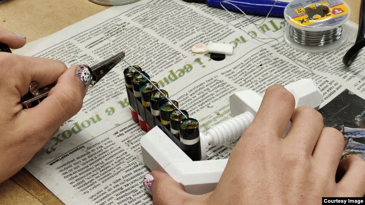 Një grua në një punëtori në Lviv duke ngjitur me shirit bateritë e cigareve elektronike të dërguara nga Leeds në një bllok që do të vendoset në një powerbank.