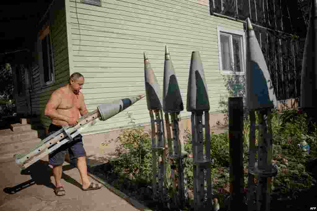A Ukrainian farmer carries the collected remains of a missile in the courtyard of his house in the village of Ruski Tyshky in the Kharkiv region.
