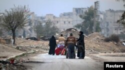 People carry their belongings as they flee the Kadi Askar area toward the Bustan al-Qasr neighborhood in the rebel-held besieged Kadi Askar area of Aleppo on December 5.