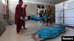 Afghan medical workers carry the bodies of two foreign women who were shot dead in Herat on July 24. 