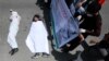 Afghan men wearing clothes spattered in blood lay down on a road as protesters shout slogans against the Iranian regime and demand justice during a protest outside the Iranian Embassy in Kabul on May 7.