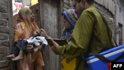 A Pakistani health worker administers the polio vaccine to a child during a vaccination campaign in Lahore on October 21, 2014.