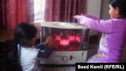 طفلتان بجوار مدفأة نفطية في احد المنازل ببغداد