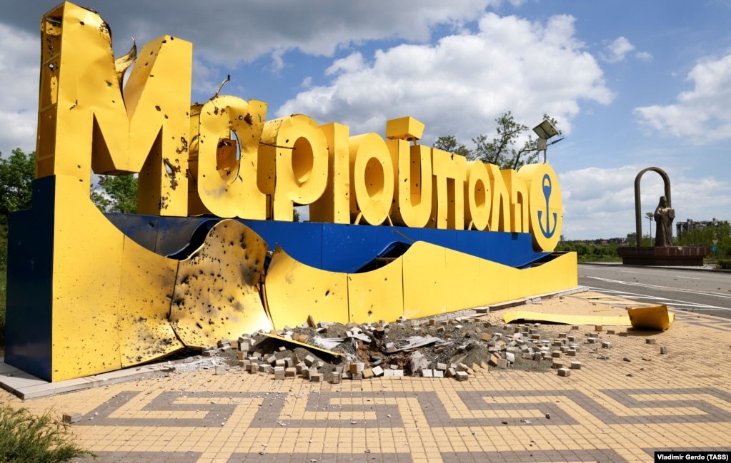 Il cartello d'ingresso danneggiato alla città di Mariupol e il monumento al metropolita Ignazio di Mariupol