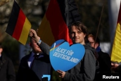 Un tânăr neamț ține un afiș cu mesajul „Alice pentru Germania” la un miting pro-AfD din Neu-Isenburg, 1 februarie 2025.