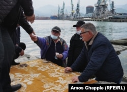 Taxi drivers gamble with dice on Batumi’s harbor waterfront.