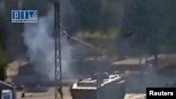 A video grab from a social media website on August 3 shows smoke rising near a tank at Al-Bahra roundabout in Hama.