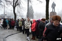 Localnici stând la coadă pentru hrană distribuită de o organizație umanitară în Donețk, 30 ian.