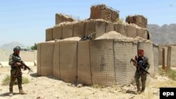 Afghan soldiers inspect the scene after overnight clashes with Taliban militants at a military base in Kandahar Province on July 26.