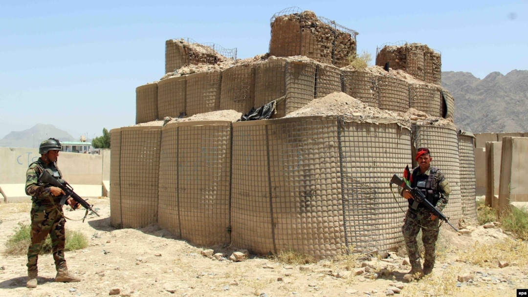 Afghan soldiers inspect the scene after overnight clashes with Taliban militants at a military base in Kandahar Province on July 26.