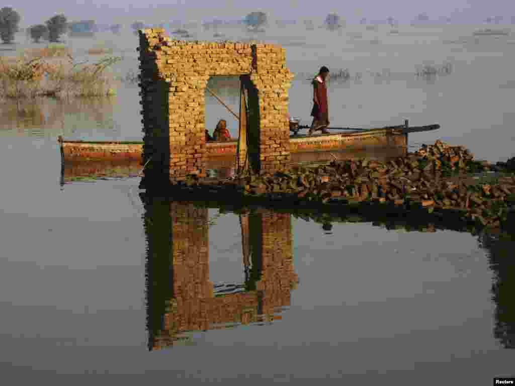 Pakistani flood victims on a boat pass by a doorway left standing after floods destroyed houses in the village of Chandan Mori Johi, in Sindh Province, on September 30. Photo by Athar Hussain for Reuters