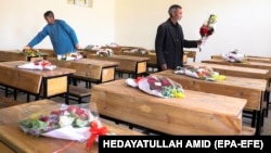 School workers puts donated bouquets of flowers from the Kabul municipality on the empty desks of students who were killed in the bombings.