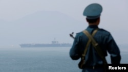 Вьетнамский солдат стоит на вахте перед американским авианосцем Carl Vinson во время его "визита дружбы" в порт Дананг. Вьетнам, 5 марта 2018 года