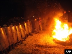 Kosovo Serbs stand in front of KFOR troops before dawn on October 20 as the NATO-led force tries to dismantle a roadblock near the village of Jagnjenica.