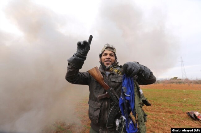 Боец одной из антиасадовских группировок, обороняющих Идлиб, держит в руках детали летного комбинезона пилота, управлявшего сбитым Ми-8 армии Асада. 11 февраля 2020 года