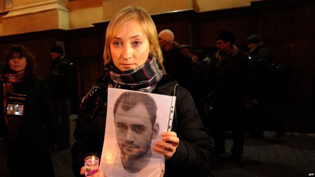 Darya Korsak, the wife of the imprisoned Alyaksandr Atroshchankau, holds her husband's portrait during a protest in front of the headquarters of the Belarusian KGB in Minsk less than a month after the disputed presidential election of December 2010.